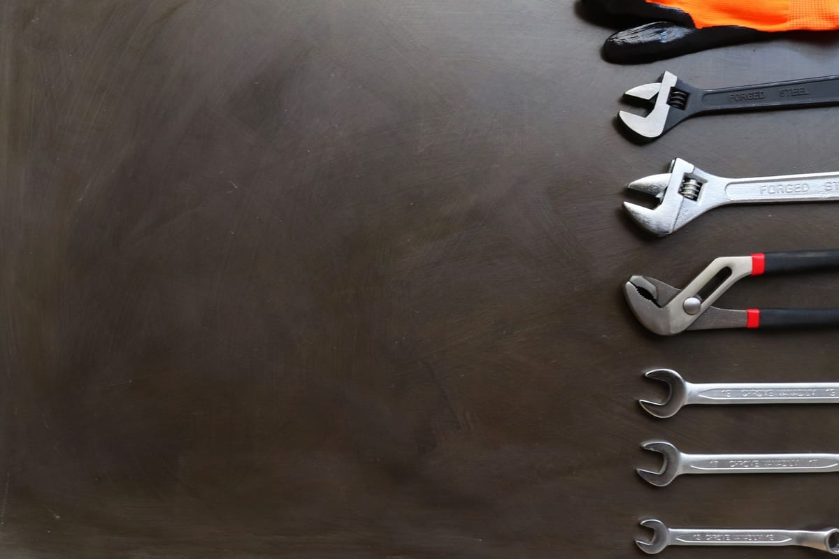 A lineup of wrenches and pliers laid out on a workbench